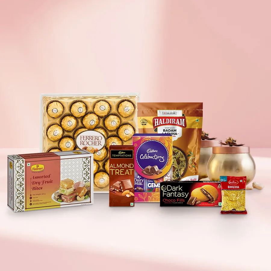 A beautifully arranged gift hamper featuring an assortment of chocolates, dry fruits, and Haldirams snacks, including Ferrero Rocher, Cadbury chocolates, Dark Fantasy Cookies, almonds, and cashews.