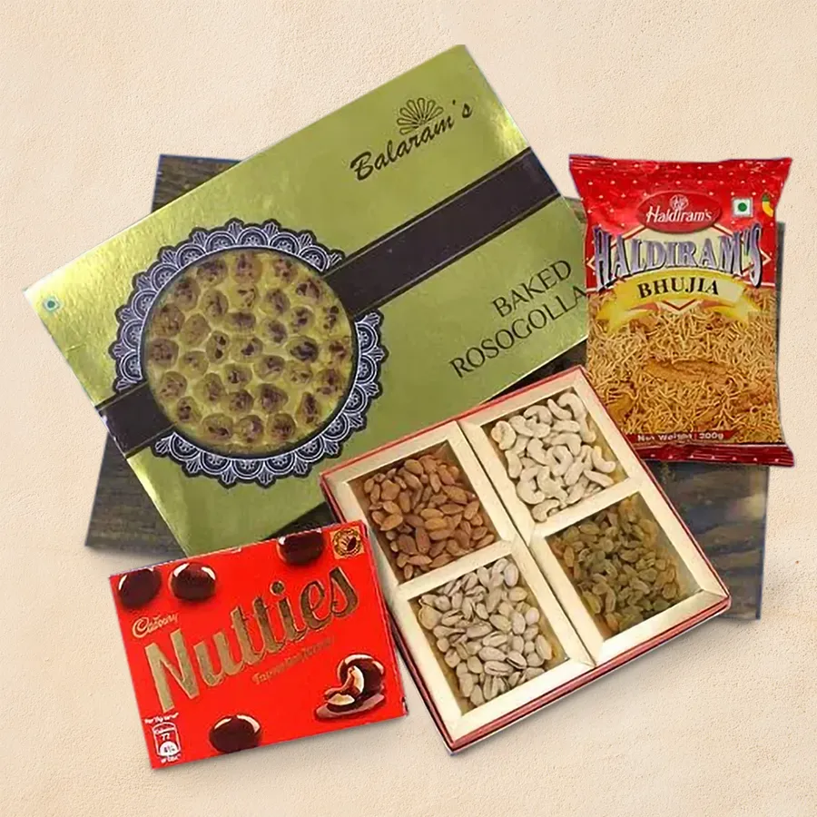 A beautifully arranged wooden tray filled with Balaram Mallick sweets, including Baked Rasgulla, assorted dry fruits, Cadbury Nutties chocolates, and Haldiram Bhujia.