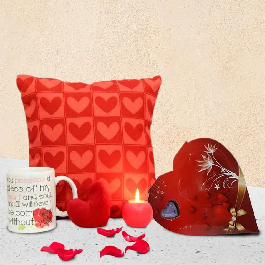 Enticing gift combo featuring heart-shaped chocolates, a plush heart toy, a cozy cushion, a glowing ball candle, and an adorable coffee mug