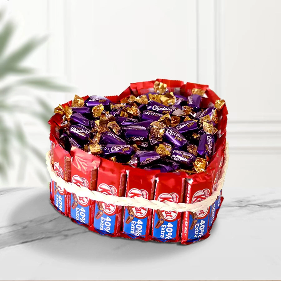 Heart-shaped bouquet filled with Nestlé KitKat chocolates and Cadbury Choclairs Gold candies, elegantly arranged on Thermocol base with white yarn.
