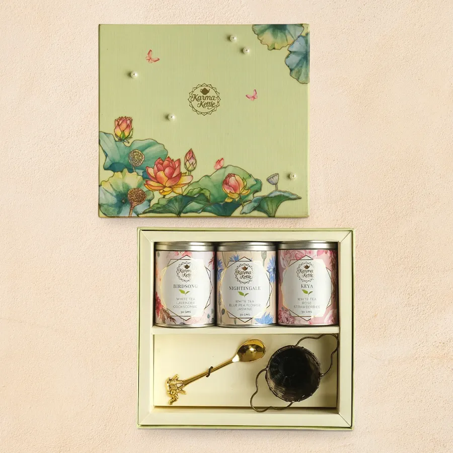 White Tea Trilogy hamper featuring three white tea blends, an antique brass tea strainer, and a brass teaspoon.