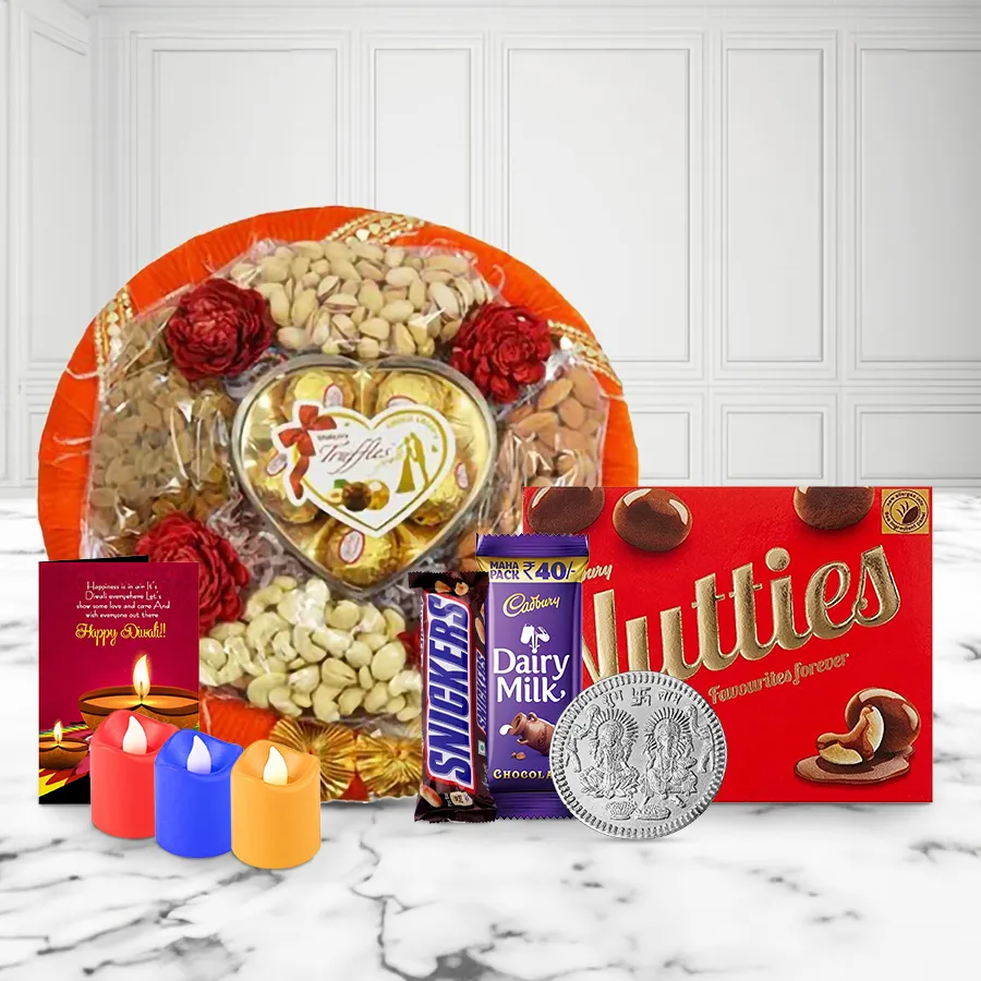 A vibrant gift tray filled with premium nuts, chocolates, tea light candles, and a silver-plated Ganesh Lakshmi coin, adorned with a festive Diwali card.