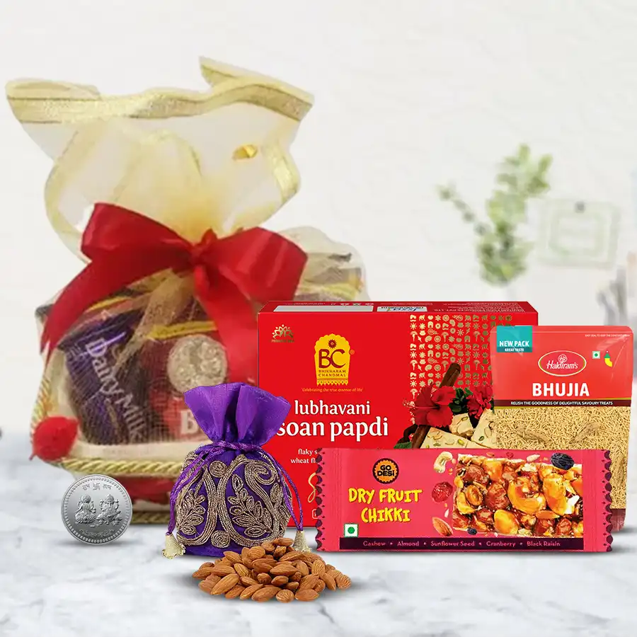Sheer Bliss Diwali sweets and dry fruits hamper featuring Soan Papdi, Bhujiya, dry fruit chiki, almond potli, and silver-plated Ganesh Lakshmi coin in a decorative basket