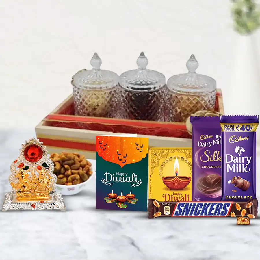 Lavish Sweet Savory Delights Hamper featuring a wooden tray filled with cashew jars, Cadbury chocolates, Snickers, a Ganesh Lakshmi mandap, a fridge magnet, and a Diwali greeting card.
