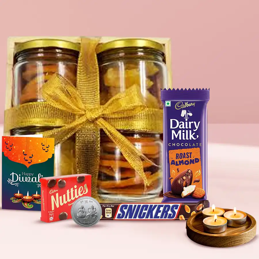 Festive Allure Diwali Assortments Hamper with wooden tray, dried orange and pineapple slices, Cadbury chocolates, Snickers, tea light candles, silver Ganesh Laxmi coin, and greetings card.