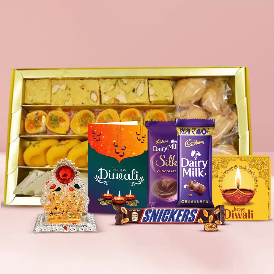 A vibrant gift hamper filled with Kaju Katli, Soan Papdi, mini samosas, savory snacks, Cadbury chocolates, Snickers, a Ganesh Lakshmi Mandap, a handmade fridge magnet, and a Diwali wishing card, decorated for the festive season.