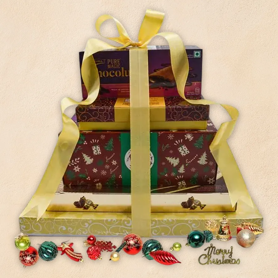 Gourmet gift tower featuring fruit cake, Ferrero Rocher, truffles, mixed nuts, crackers, cookies, and cheese, decorated for Christmas.