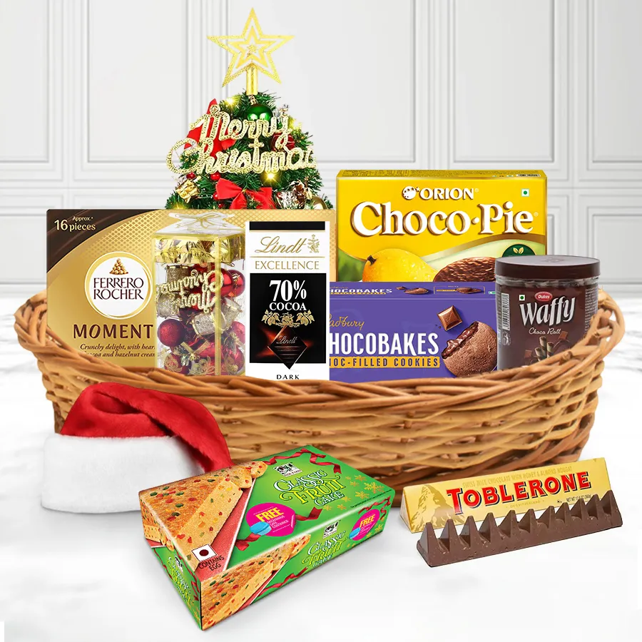 A festive basket filled with various chocolates and treats, decorated with Christmas ornaments and topped with a tree cap.