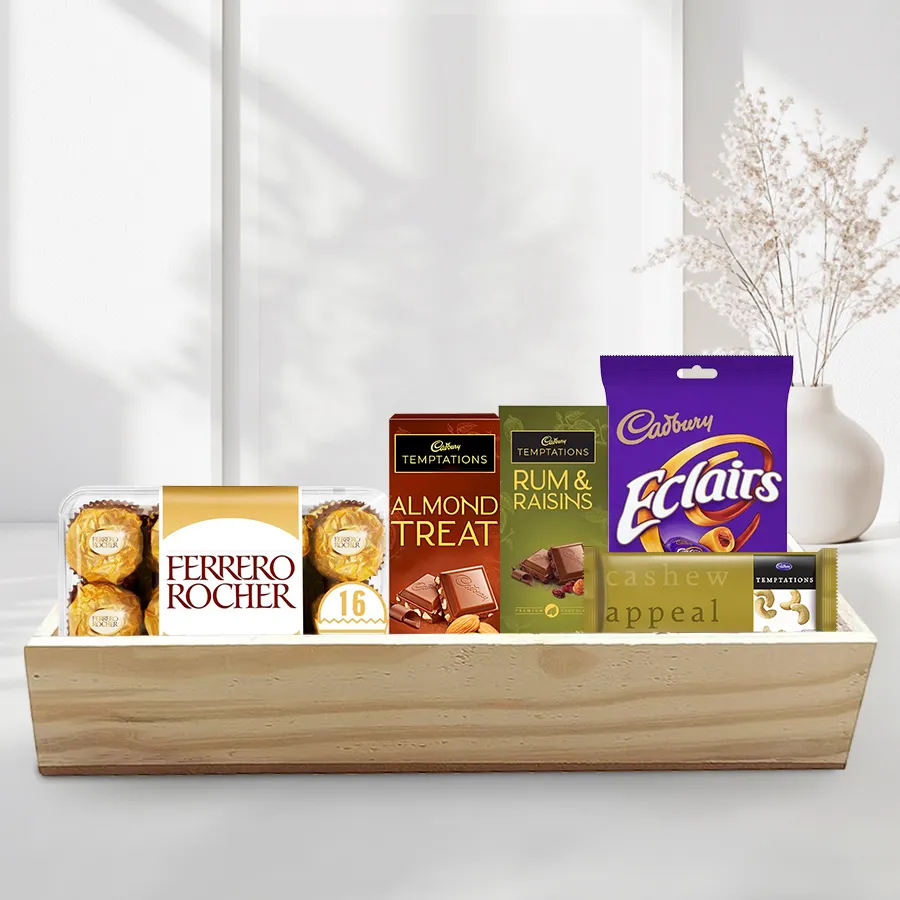 Absolute Indulgence Chocolate Tray featuring Ferrero Rocher chocolates, Cadbury Temptation bars in Rum & Raisins, Cashew, and Almond flavors, and Cadbury Eclairs arranged on a stylish wooden tray for Christmas.