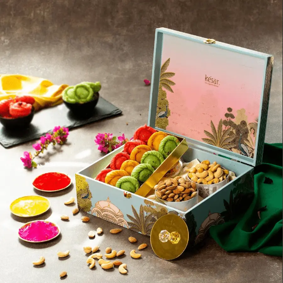 Tasty Sweets N Nuts Holi Gift Box featuring Rose, Kesar & Pistachio Chandrakala, roasted cashews and almonds, and a Holi greeting card in a premium box
