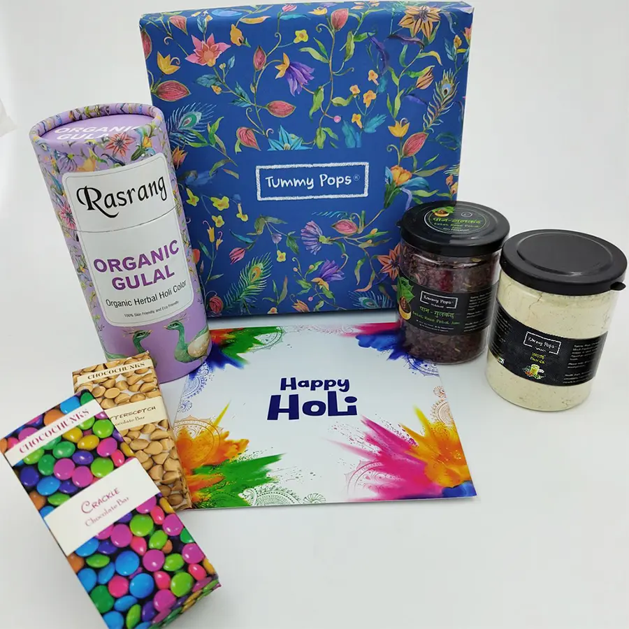 Ultimate Holi Hamper featuring assorted treats including chocolate bars, Paan Gulkand, Thandai, Gulal, and a Holi greeting card.
