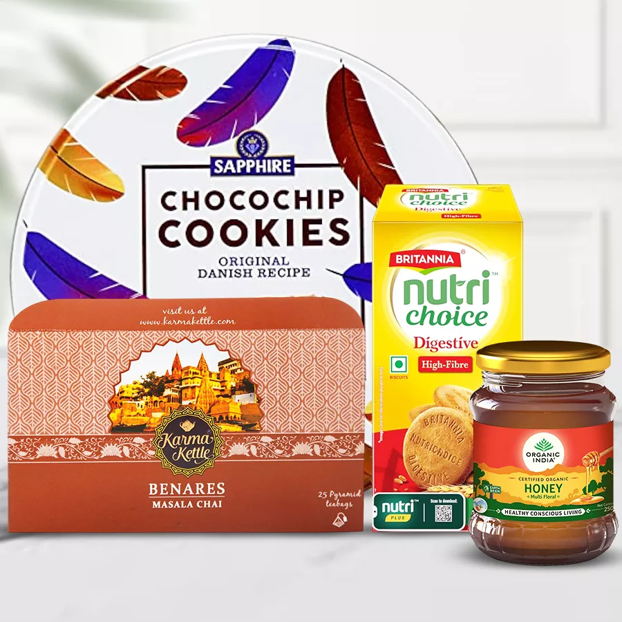 Delicious Snacks with Olives N Cutting Masala Chai Hamper featuring chai, cookies, biscuits, and honey arranged on a decorative background.