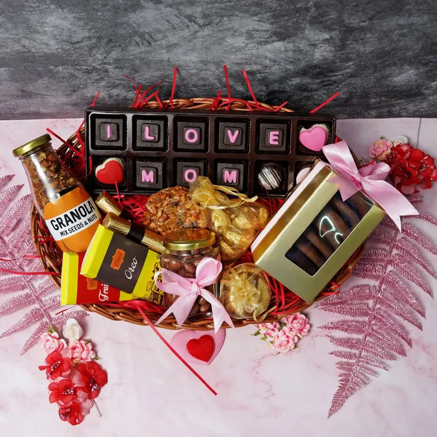 A charming cane basket filled with assorted chocolates, a granola jar, chocolate bars, almond florentines, mixed nuts cookies, chocolate-coated raisins, assorted cookies, and chocolate logs, ideal for Mother's Day.