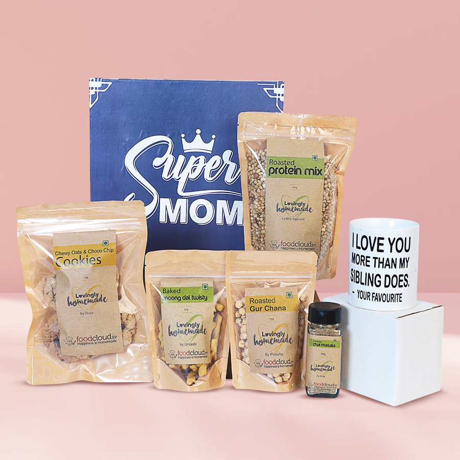 Wholesome box of healthy treats for mom featuring a mug, cookies, moong dal twists, protein mix, and chai masala
