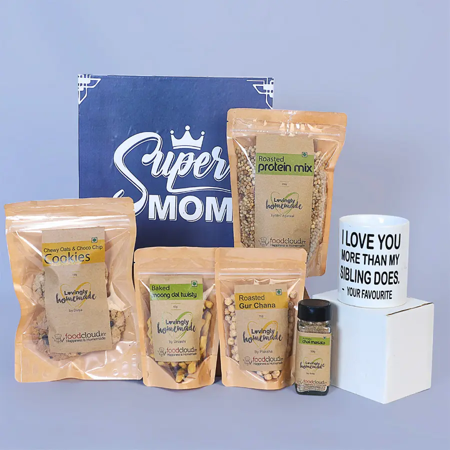 A beautifully crafted coffee mug surrounded by Oats N Almonds cookies, Choco Chip cookies, Baked Moong Dal Twisties, Roasted Protein Mix, and Chai Masala, arranged for Mother's Day celebration.