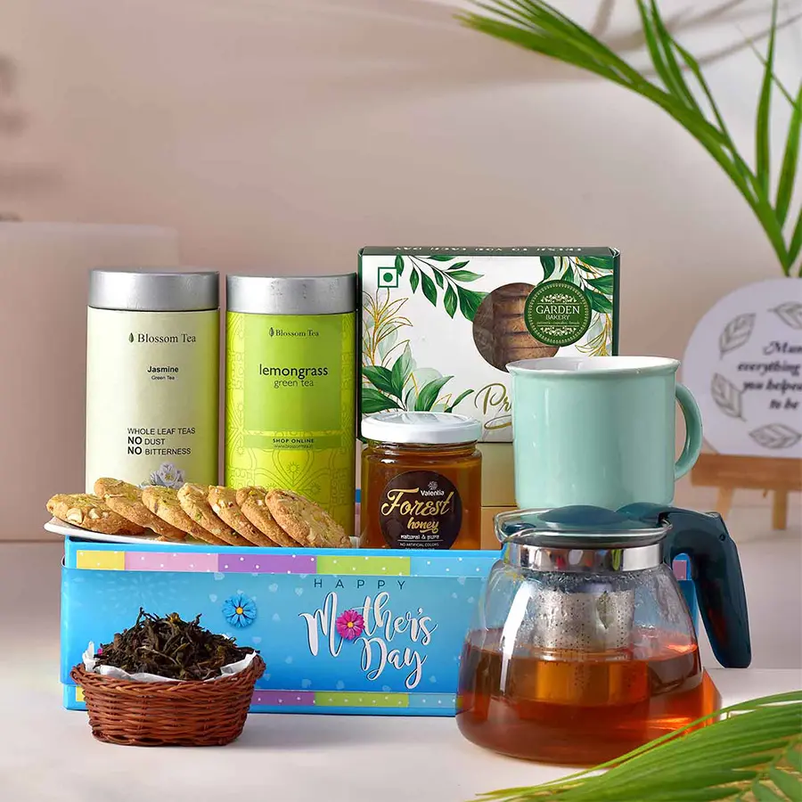 Tea time hamper for mom featuring lemon grass tea, jasmine green tea, a tea kettle, a mug, dry-fruit cookies, honey, and a designer tray.