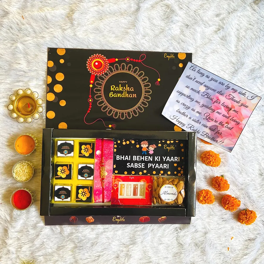 Chocolaty Rakhi Wishes hamper featuring a metal rakhi, assorted creamy chocolates, crunchy almonds, a rich chocolate bar, Roli Tikka, Mishri, and a greeting card.