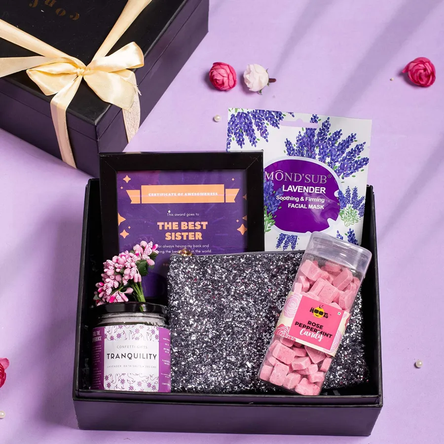 Sisters Special Rakhi Gift arrangement featuring a Best Sister Award Frame, Hoots Rose Peppermint Candy, a silver glitter pouch, lavender bath salts, a Mondsub lavender sheet mask, and a black signature box.