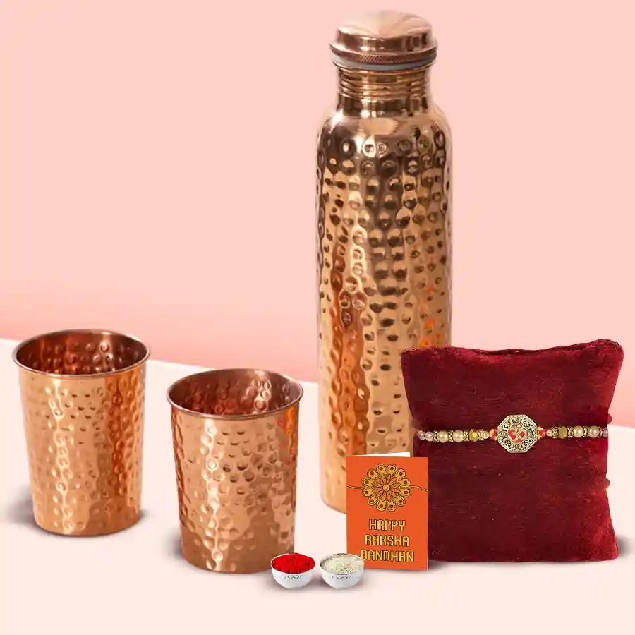 Sacred OM Rakhi and hammered copper bottle with two glasses, Roli, Tika, Chawal, and a heartfelt message card.