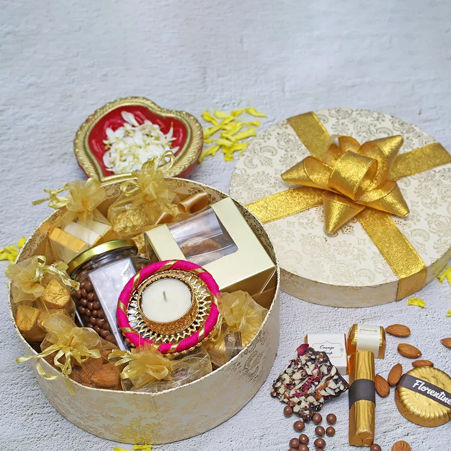 Luxurious gold-toned gift box filled with assorted gourmet treats for Diwali celebration, including cookies, chocolates, pralines, and a decorative diya.