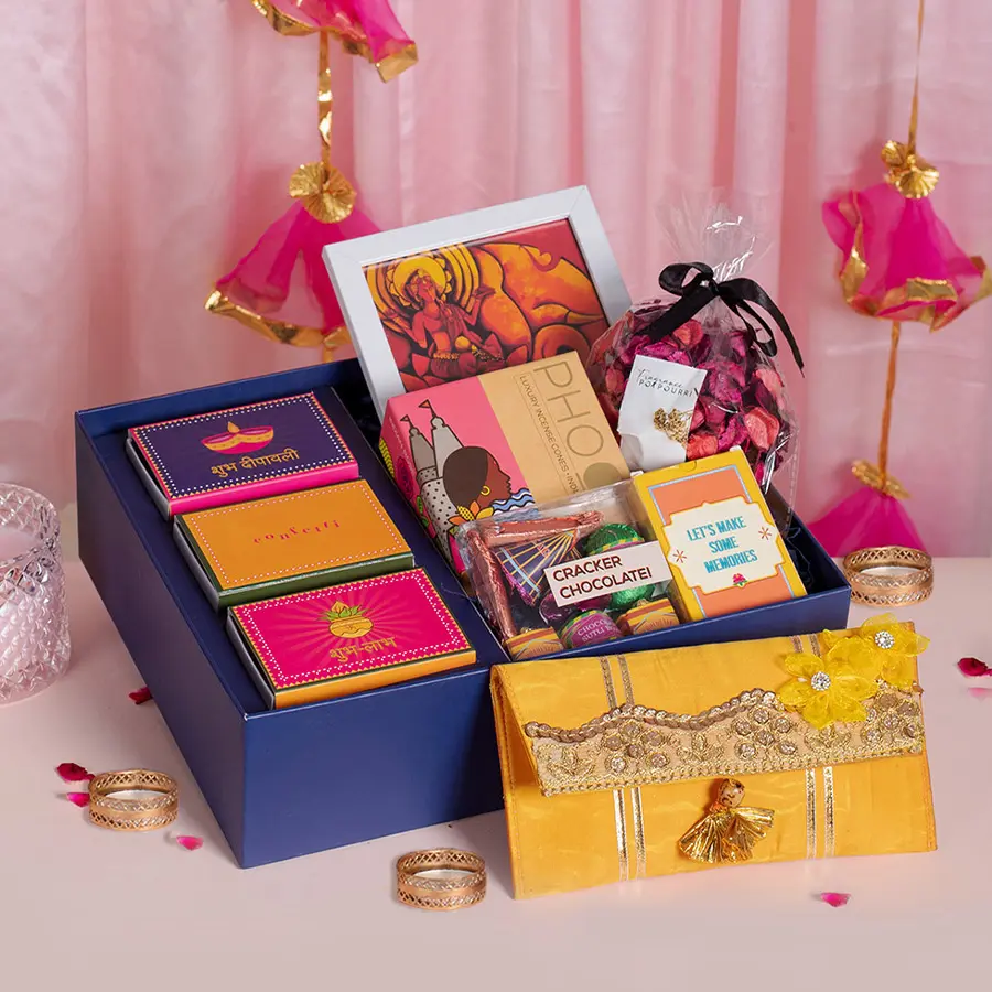 Complete Diwali Celebration Kit featuring Laxmi Ganesh frame, assorted nuts, sweet cracker chocolate, playing cards, incense, candles, pink potpourri, rangoli colors, QR code for Pooja Aarti playlist, and a reusable box.