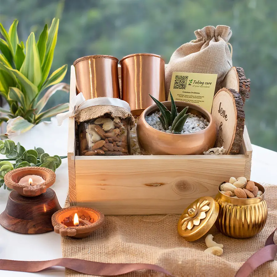 Diwali Copper Glass and Coasters Gift box with elegant copper glasses, Love N Light coasters, a jar of mixed nuts, stylish copper planter, green potpourri in jute potli, all arranged in a personalized pinewood box