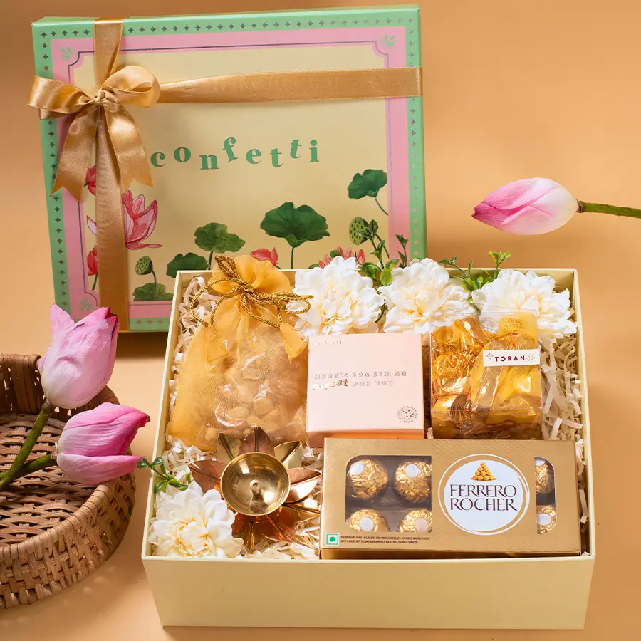 Organza potli filled with Ferrero Rocher chocolates, Brass Diya Torans, mixed dry fruits, and handmade chocochip cookies in a Green Lotus box.