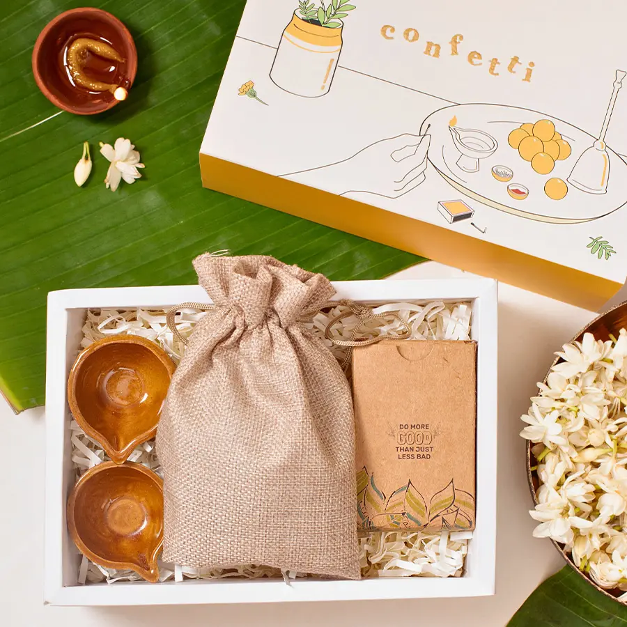Festive Fusion Nutty Diwali Joy Box with ceramic diyas, mixed nuts in a jute potli, eco-friendly playing cards, and vibrant marigold slider box.