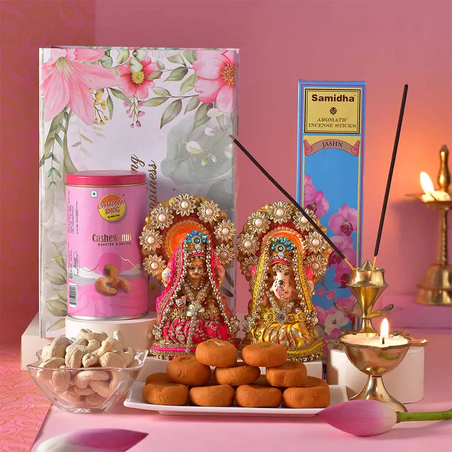 Divine Diwali Clay Deities and Sweets Box featuring Laxmi and Ganesh idols, brass deepak, Keasr Peda, roasted cashews, Samidha incense sticks, and brass Agardaan Tarakamal in a festive package.