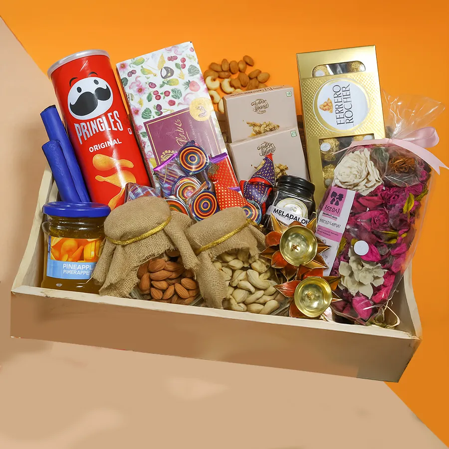 A beautifully arranged Diwali surprise hamper featuring designer jute-tied cashews and almonds, Ferrero Rocher chocolates, Pringles, Karma Kettle Fruitea, Melabalo Honey, Chabaa Orange Jam, Nutty Affair almond bites, cracker-shaped chocolates, Iris Rose potpourri, brass diyas, and a chic wooden tray.
