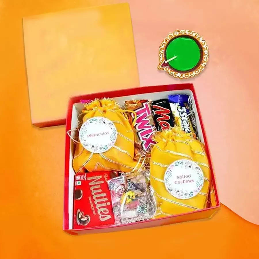 Diwali hamper featuring Mars and Twix chocolates, a beautiful Diya, salted cashews, rich pistachios, and Cadbury Five Star and Nutties.