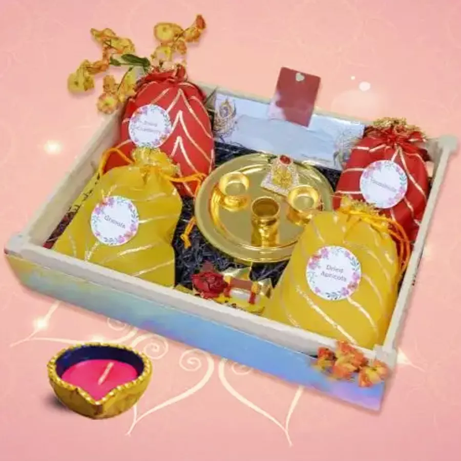 Diwali hamper featuring a decorative Diya, dried cranberries, sweet apricots, crunchy hazelnuts, and granola in an elegant packaging.