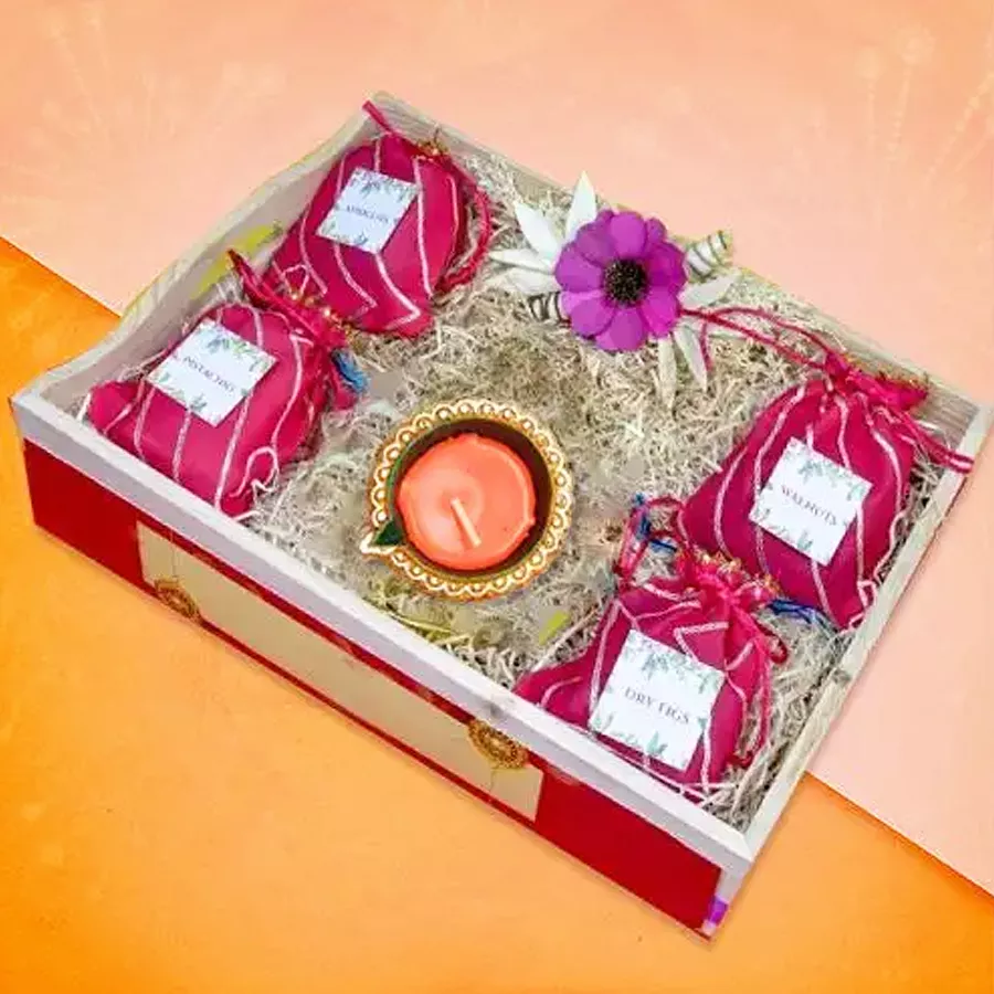 Diwali wellness hamper featuring a Diya and 200g servings of pistachios, walnuts, dry figs, and apricots in elegant packaging.