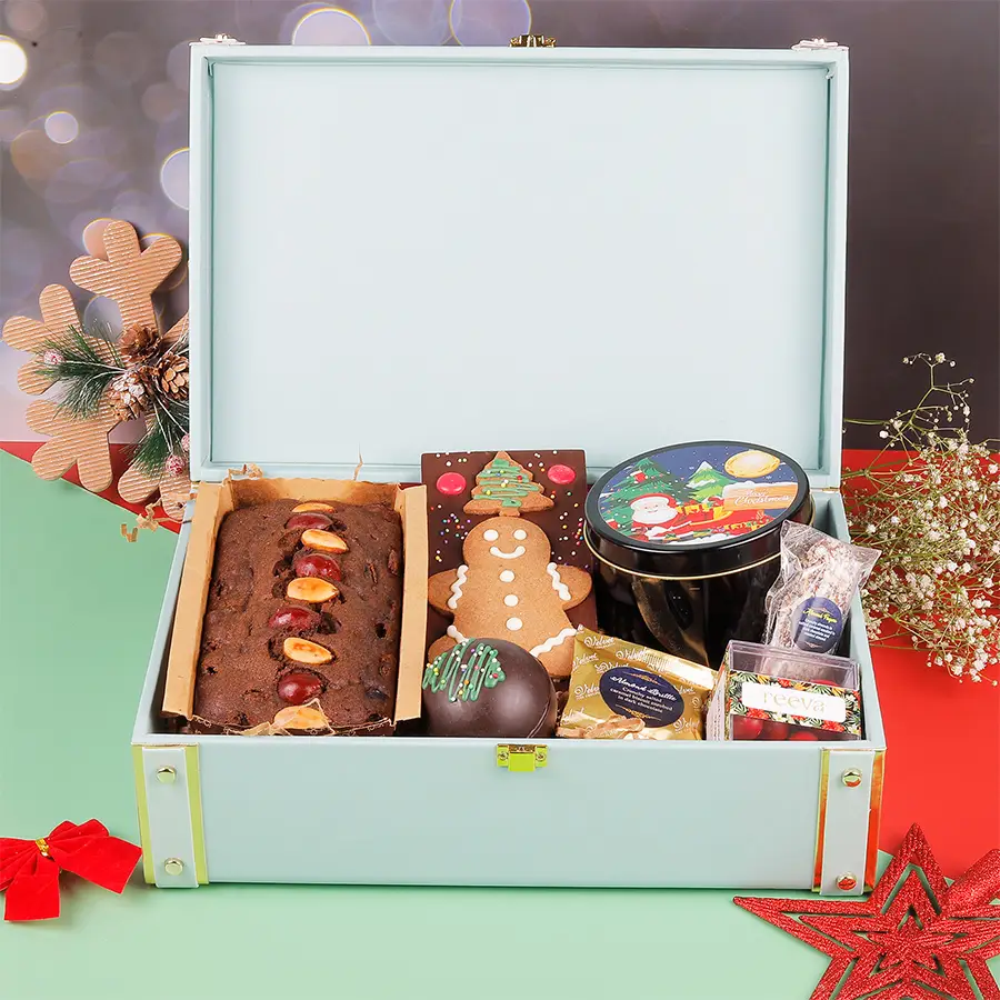 Perfect Holiday Surprise Gift Hamper filled with festive treats including plum cake, chocolate & cookie bar, hot chocolate bomb, snickerdoodle cookies, cranberry dragees, almond brittle, and almond fingers in a beautifully packaged box.