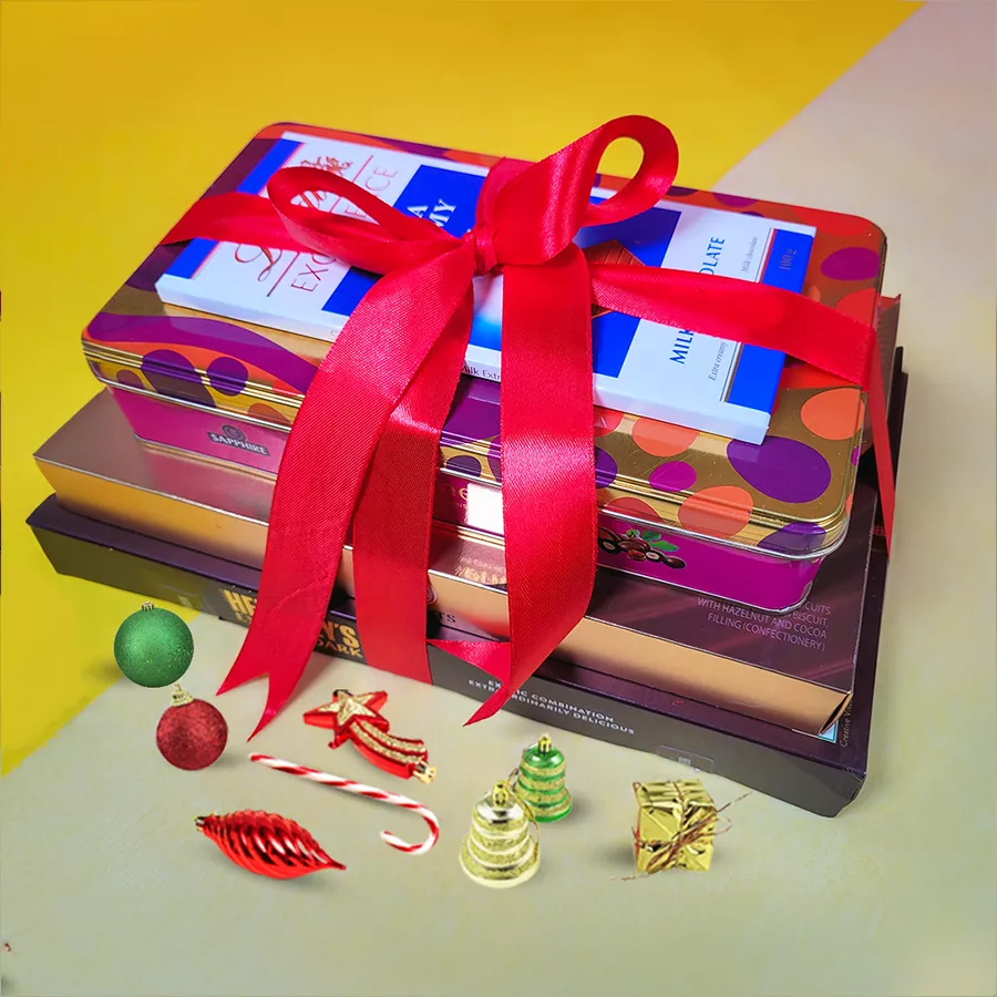 Exquisite Christmas Chocolate Tower with Hershey’s Exotic Dark Chocolates, Ferrero Rocher Moments, Sapphire Almond-Coated Chocolates, and Lindt Excellence Milk Chocolate, beautifully arranged in a festive gift-wrapped tower with a ribbon.