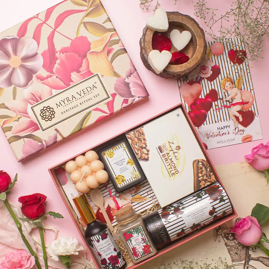 Luxurious Myra Veda Gift Hamper featuring a vegan soy candle, almond brittle chocolates, pure rose water, organic clay, lotion, gold soap, and a personalized greeting card arranged beautifully in an elegant box.