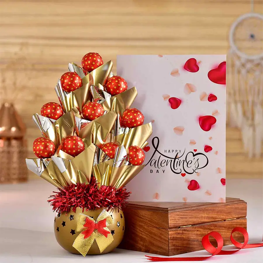 Handmade chocolates in a heart-shaped box beside a sleek metal T light holder and a Valentine’s Day card.