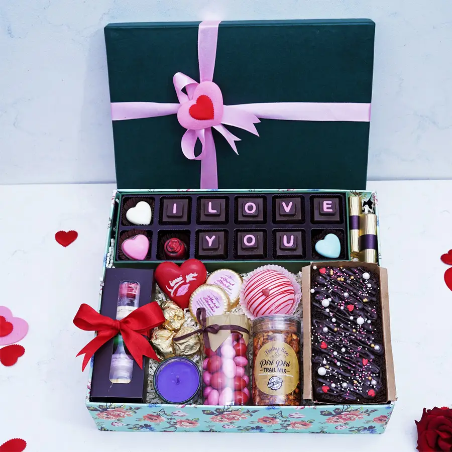 Chocolaty Symphony Gift Box featuring rich chocolates, almond treats, strawberry logs, macarons, a cozy candle, and a hot chocolate bomb arranged elegantly in a festive presentation.
