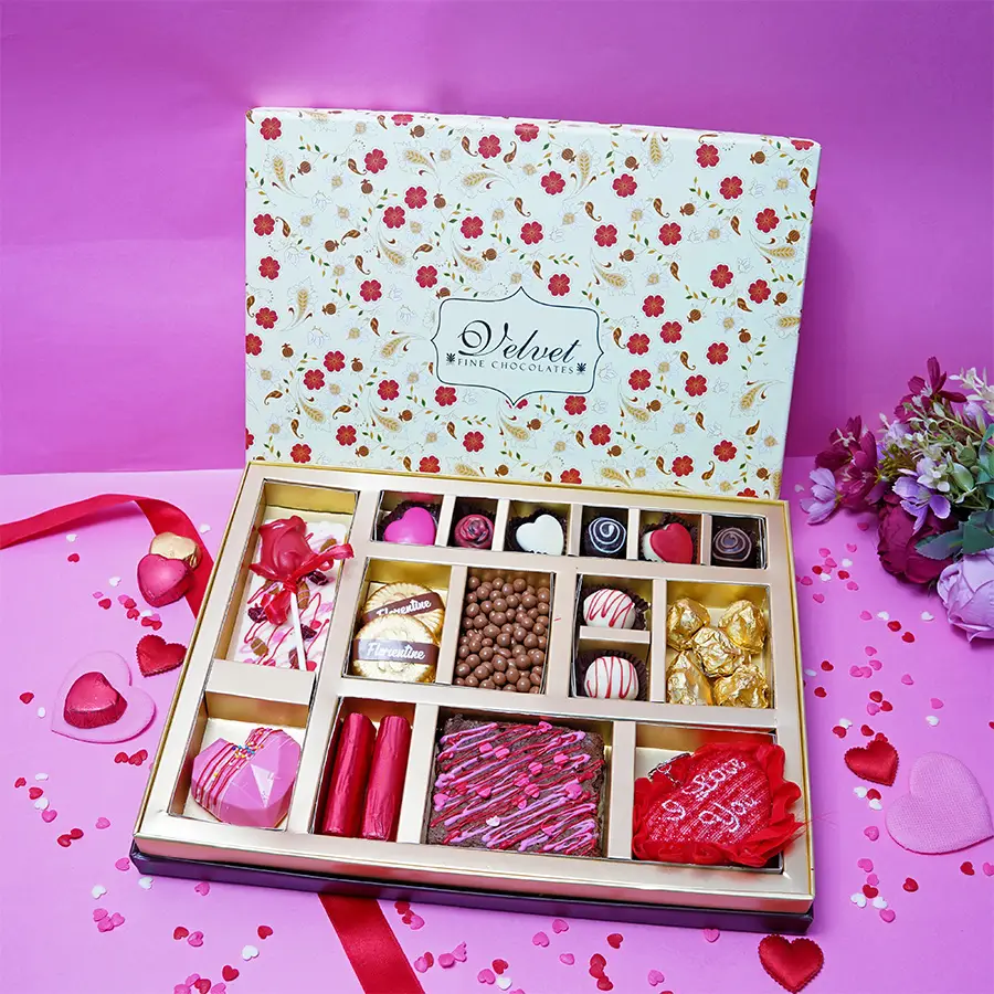 Deluxe Chocolates Treat Gift Box featuring assorted chocolates, Cranberry Truffles, Strawberry Crisp Logs, Fruit N Nut Bar, Chocolate Pinata Heart, Chocolate Brownie, Coated Butterscotch, Almond Rocks, Rose Lollipop, and a heart-shaped keychain.