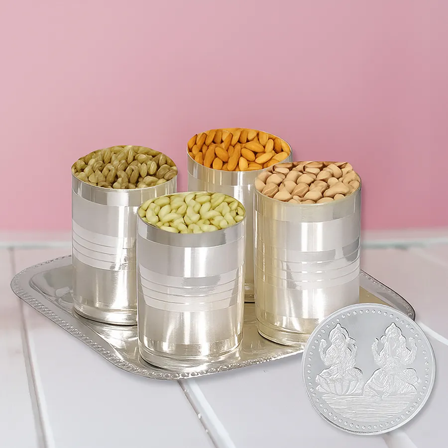 Dry fruits in silver-plated glasses on a silver tray with a Laxmi Ganesh coin