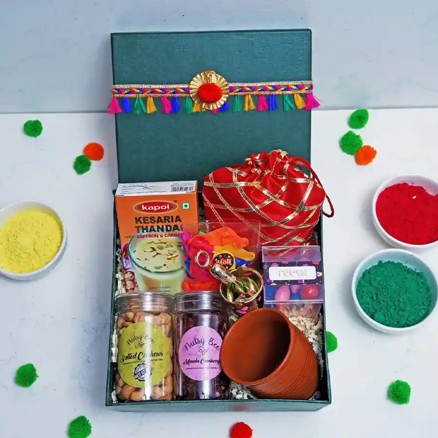 Flavourful Treats N Holi Harmony Hamper featuring Kesaria Thandai, Strawberry Crisp Logs, assorted dragees, salted cashews, masala cranberries, Kullad Cup, festive balloons, and a Laddu Gopal Pichkari, all arranged for Holi celebrations.