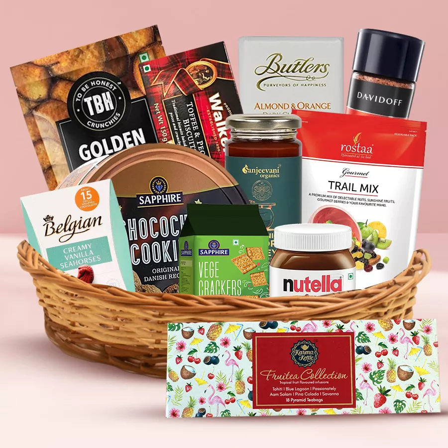 A beautifully arranged gift hamper filled with premium snacks and treats including cookies, chocolates, biscuits, and coffee, presented in a reusable basket.