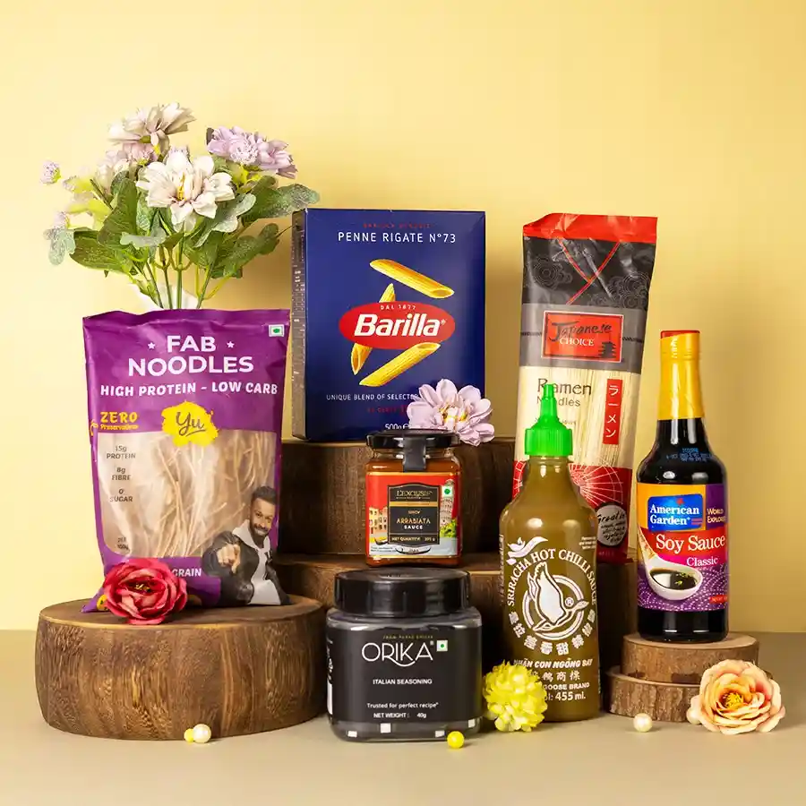 Decadent Pasta N Noodle Fusion Set featuring Barilla Penne, Japanese Ramen, LExclusif Arrabbiata Sauce, Orika Italian Seasoning, Flying Goose Sriracha, and American Garden Soy Sauce arranged aesthetically.
