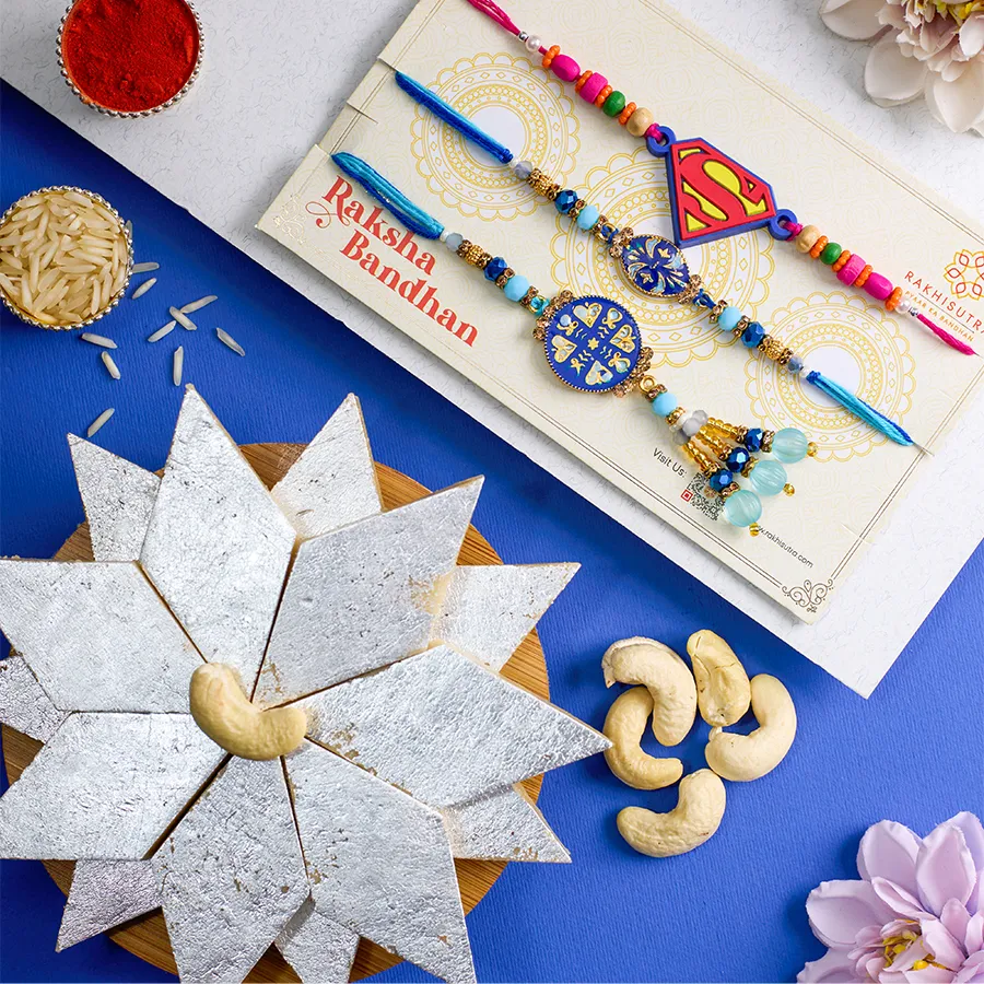 Trendy Family Rakhi Set featuring Kundan Bhaiya Bhabhi Rakhi, Superman Rakhi, 250g Kaju Katli, Roli, Tika, Chawal, and a heartfelt message card