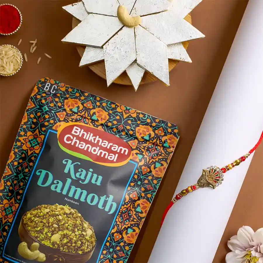 Elegant Kundan Rakhi alongside Kaju Katli and Kaju Dalmoth treats, with Roli Tika, Chawal, and a message card for Raksha Bandhan celebration.