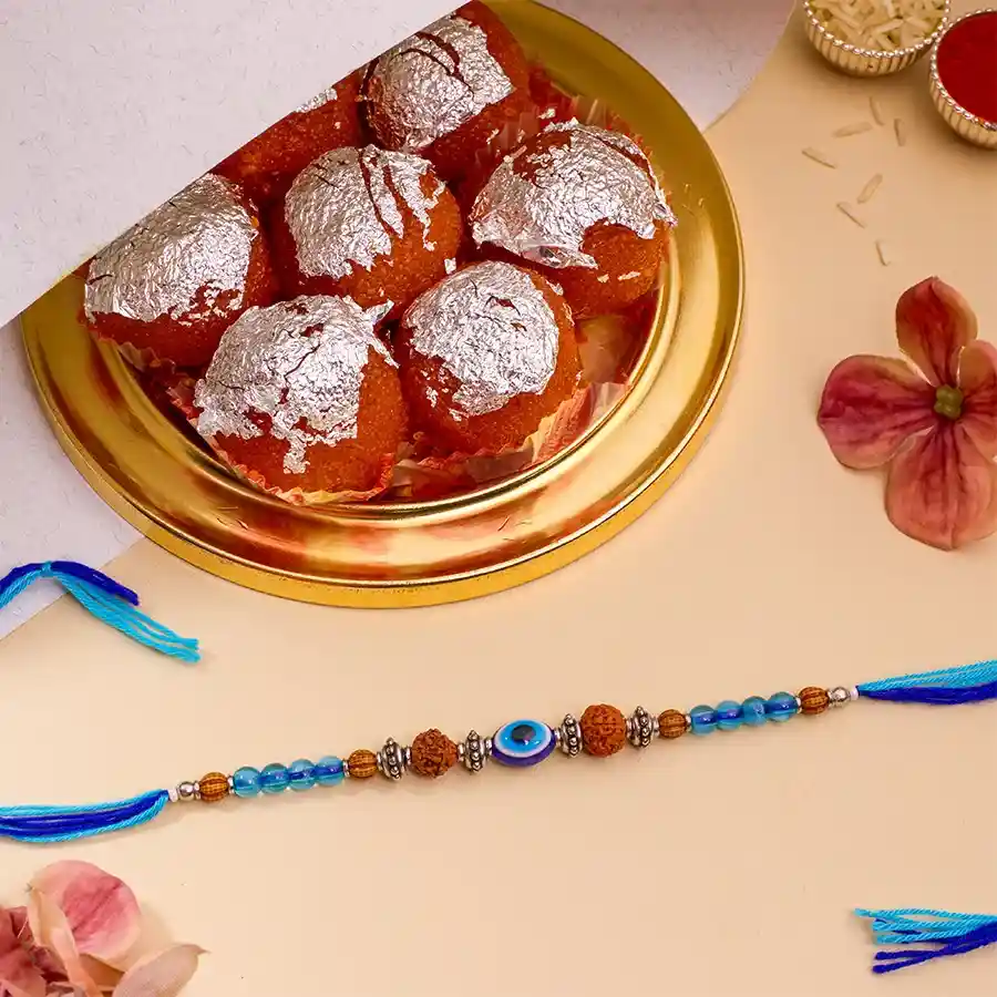 Charming Evil Eye Rakhi with Ghee Laddu Combo, including Rakhi, Ghee Laddus, Roli Tika, Chawal, message card, and extra Rakhi.