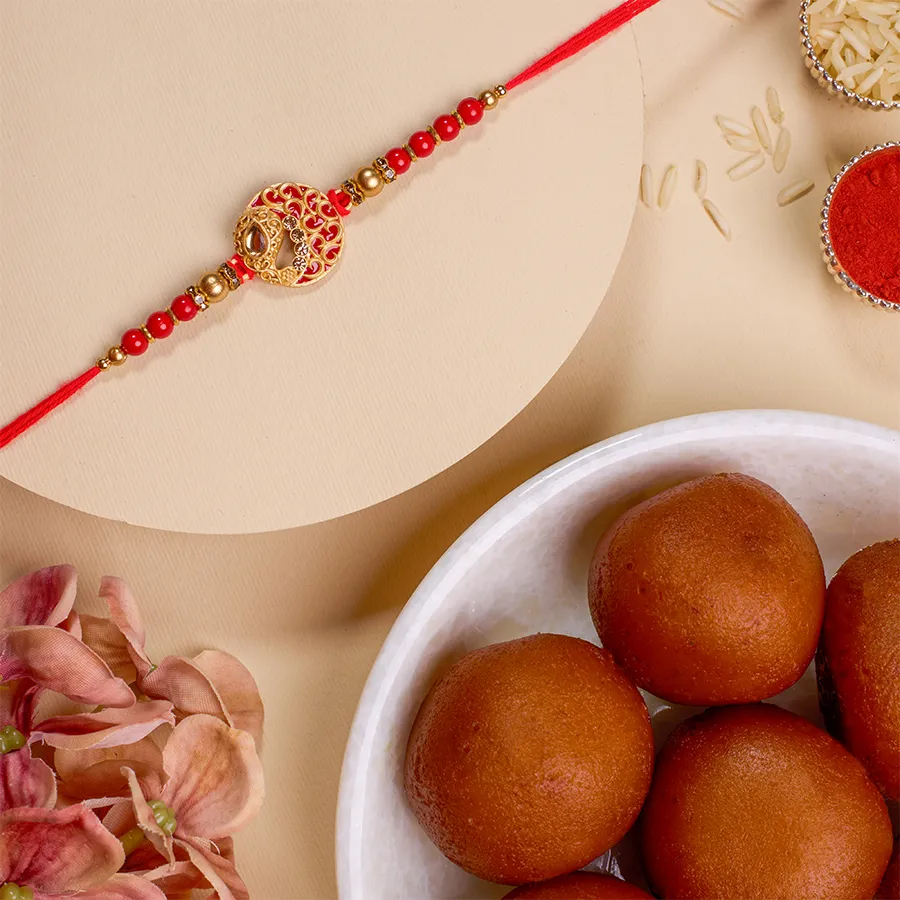 Festive Kundan Rakhi set with intricate designs, 500g of Gulab Jamun, Roli, Tika, Chawal, and a personalized message card