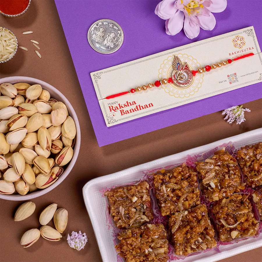 Magnificent Rakhi gift set featuring a Shree Krishna Rakhi, Dodha Barfi, crunchy pistachios, a silver coin, Roli Tika, Chawal, a heartfelt message card, and an extra Rakhi, all beautifully packaged.