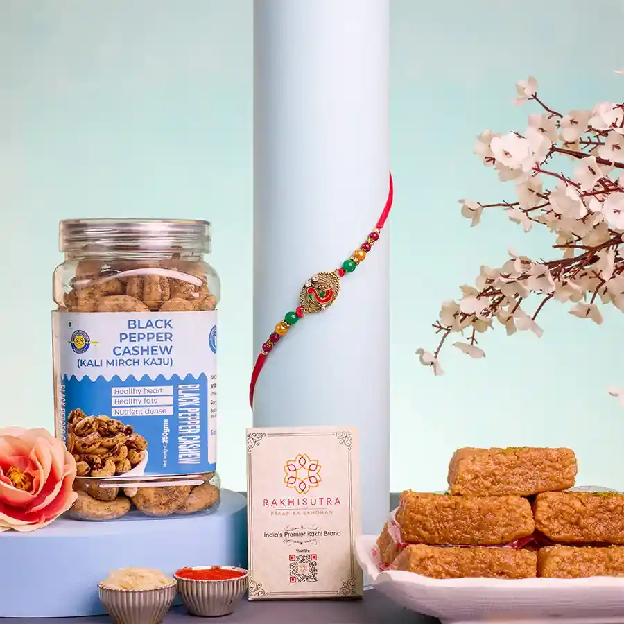 Festive Kundan Rakhi and Treats Delight Set featuring a Kundan Rakhi, Mini Milk Cake, Black Pepper Cashew jar, Roli Tika, Chawal, and a personalized message card