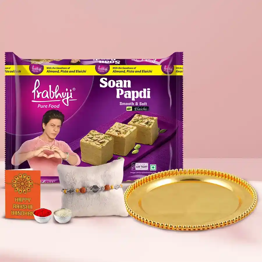 Gold-plated thali with a box of Soan Papri and Rakhi, Roli Tilak, and Chawal for Raksha Bandhan celebration